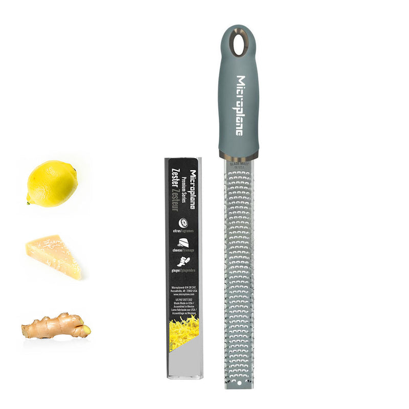 Microplane Premium Zester Grater with packaging, alongside lemon, cheese, and ginger, showcasing its versatility for zesting and grating in culinary tasks.