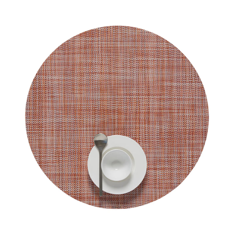 Chilewich | Mini Basketweave Round Placemats, Cinnamon, with a woven texture, featuring a white bowl on a saucer and a teaspoon on the placemat.
