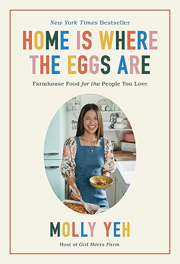 Front cover of 'Home Is Where The Eggs Are' cookbook by Molly Yeh, featuring cozy farmhouse recipes. Includes a smiling photo of the author in her kitchen.