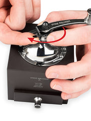 Peugeot | Roellinger Pepper Mill, Chocolate: A hand-cranked, stainless steel and wood spice grinder, held steady for precise milling, designed by chef Olivier Roellinger.