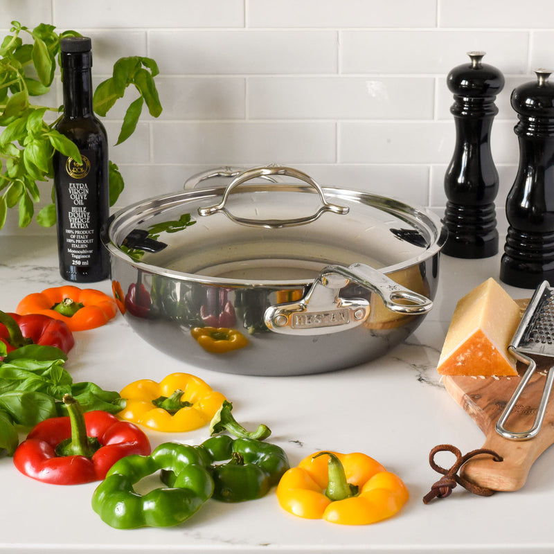 Hestan | NanoBond Cookware, 5qt Essential Pan + Lid with basil, bell peppers, olive oil, cheese, and salt-pepper mills, perfect for fresh culinary creations.