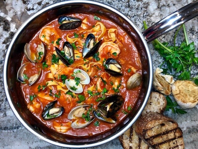 Hestan NanoBond Cookware, 3.5qt Essential Pan + Lid, filled with seafood pasta, showcasing its wide base and ergonomic handle on a stone countertop.