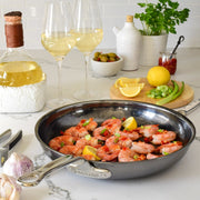Hestan NanoBond | Cookware, 11 Titanium Skillet with shrimp, chili, and lemon on a kitchen counter, surrounded by wine, garlic, and herbs.