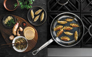 Hestan NanoBond 11 Titanium Skillet pan-fries dumplings, showcasing its durable, scratch-resistant surface amidst a culinary setup with dumpling ingredients and sauces.