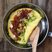 Hestan NanoBond | Cookware, 8.5 Titanium Skillet with omelette topped with bacon, mushrooms, onions, cheese, and microgreens, showcasing its superior cooking surface and ergonomic handle.