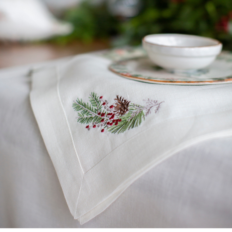 Arte Italica & Crown Linen Designs | Natale Sprig Napkin - Cream, features a pine-cone and berry motif, perfect for holiday tables. Shown with a bowl on a plate.