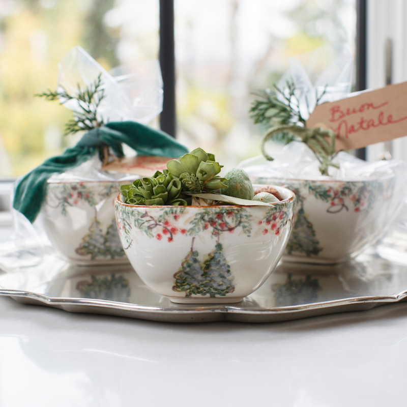 Arte Italica & Crown Linen Designs Natale Small Square Bowl on a silver tray with succulents, alongside wrapped bowls, adorned with festive greenery and a Buon Natale tag.