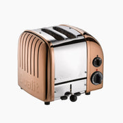 Dualit | 2 Slice Classic Toaster, Copper, featuring wide slots, manual lift, crumb tray, rotary controls, handmade quality, and defrost function, ideal for kitchen enthusiasts.
