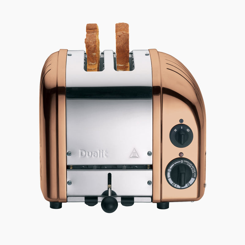 Dualit | 2 Slice Classic Toaster, Copper, with bread slices in slots, features browning and defrost controls, showcasing craftsmanship and functionality from Athens Cooks.