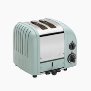 Dualit | 2 Slice Classic Toaster, Eucalyptus: Mint-green toaster with wide slots, stainless-steel top, defrost function, and rotary controls, showcasing quality craftsmanship.