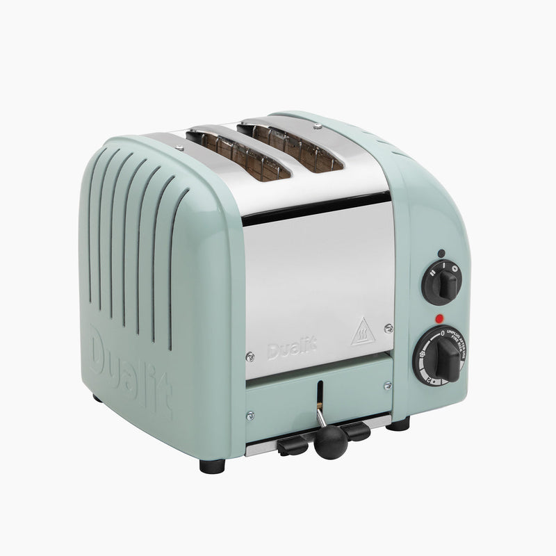 Dualit | 2 Slice Classic Toaster, Eucalyptus: Mint-green toaster with wide slots, stainless-steel top, defrost function, and rotary controls, showcasing quality craftsmanship.