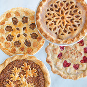 Nordic Ware | Naturals® High Dome Covered Pie Pan showcasing several pies with intricate designs, ideal for keeping baked goods fresh without squashing toppings.