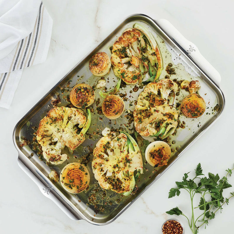 Hestan Provisions | OvenBond Tri-Ply Bakeware featuring roasted cauliflower steaks and onions with herbs and capers, showcasing even heat distribution and stylish design.