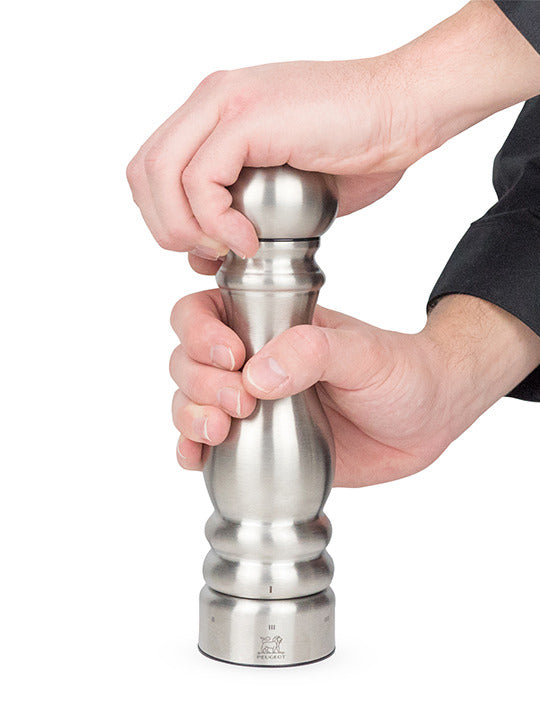 The Peugeot | Paris Chef u'Select Pepper Mill, 9 inches, is shown in use, highlighting its stainless steel finish and adjustable grinding mechanism.
