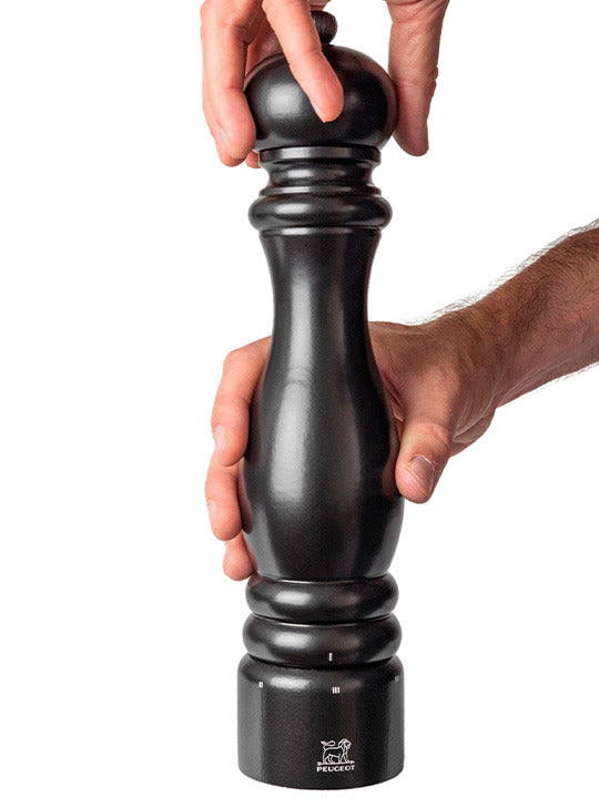 Peugeot | Paris u'Select Wooden Pepper Mill in Satin Black, held and twisted by hands, showcasing its elegant design and precision grinding mechanism.