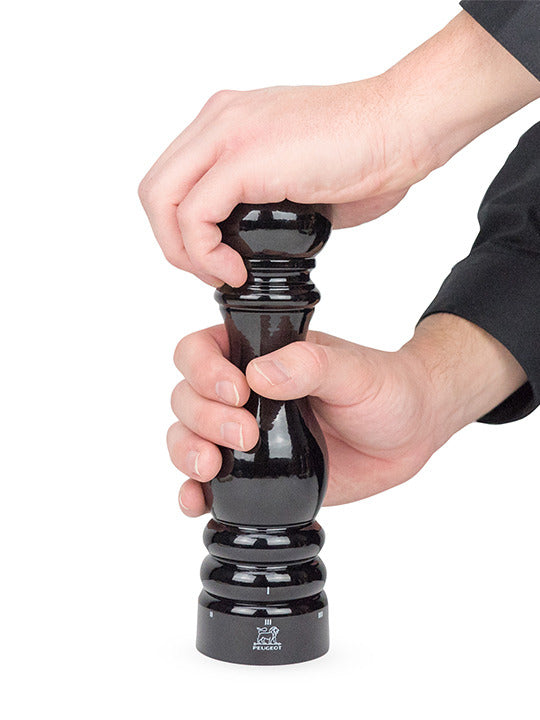 Hands turning the Peugeot | Paris u'Select Pepper Mill, Black Lacquer Wood, 9 inches, showcasing its sleek design and efficient grinding mechanism.