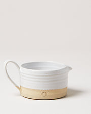 Farmhouse Pottery | Silo Sauce Boat: Handcrafted ceramic pitcher with a white glazed top, natural stoneware base, handle, and stamped wreath motif. Perfect for serving sauces.