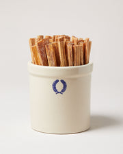 Farmhouse Pottery | Laurel Fireside Crock filled with natural wood fire starters, featuring a blue laurel emblem, ideal for adding rustic charm to your hearth.