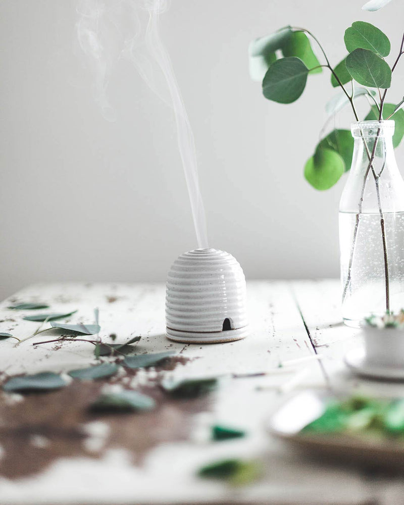 Farmhouse Pottery | Beehive Burner on a table with eucalyptus, emitting a gentle smoke plume, enhancing ambiance and deterring bugs.