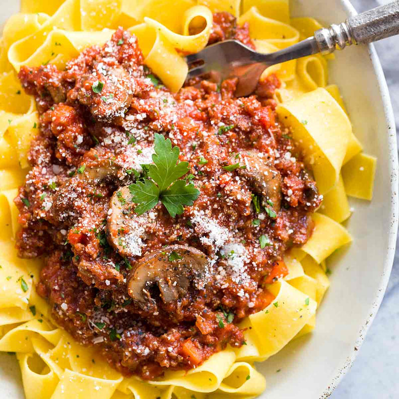 Wide ribbon pasta with chunky tomato-meat sauce, mushrooms, cheese, and parsley, showcasing the Pappardelle & Authentic Bolognese: A Regional Italian Experience workshop.