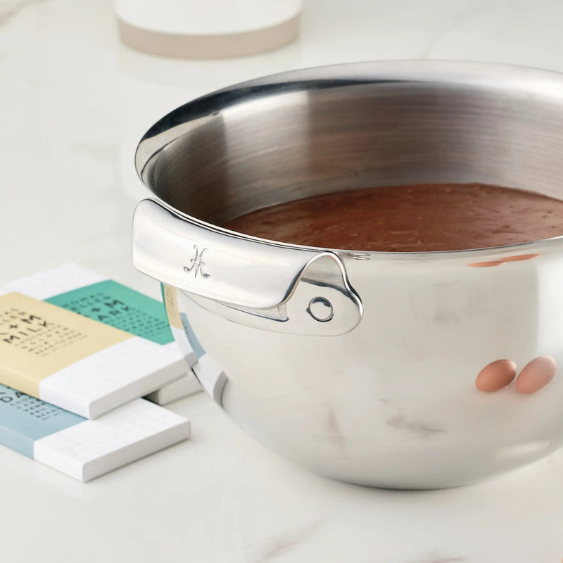Hestan Provisions | 7qt Stainless Steel Mixing Bowl filled with chocolate batter, showcasing polished handles and engraved M, beside pastel-wrapped MILK chocolate bars.