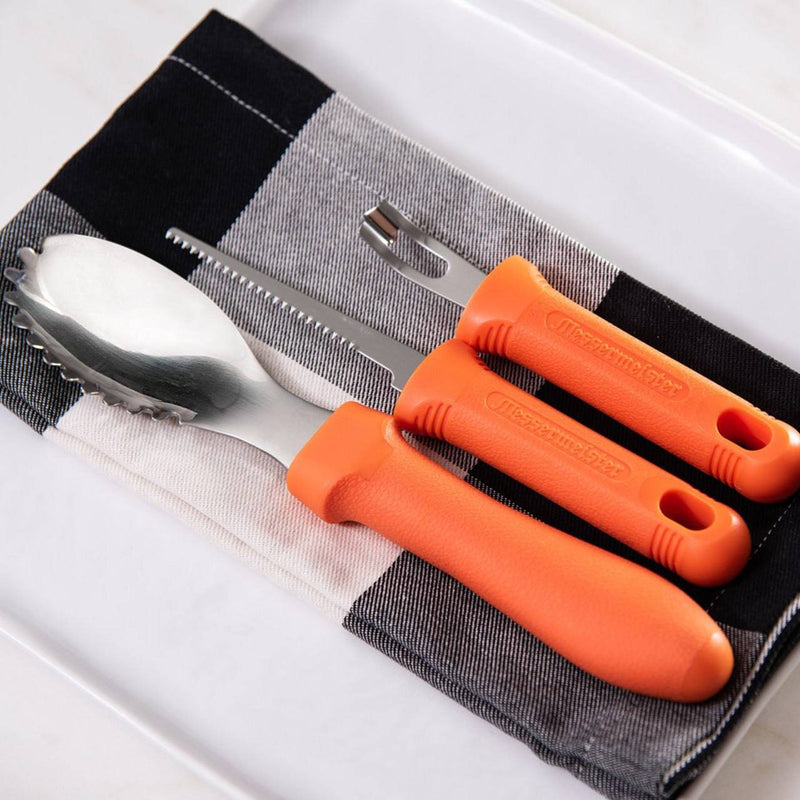 Messermeister | Pumpkin Meister Carving Set with orange handles: two-tine fork, serrated knife, and scalloped spoon on checkered cloth, ideal for precision pumpkin carving.