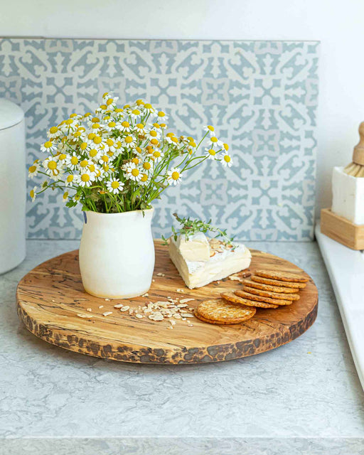 Peterman's Boards and Bowls 20 Lazy Susan - Spalted displayed with a vase of flowers and crackers, showcasing its artisanal craftsmanship and smooth rotation.