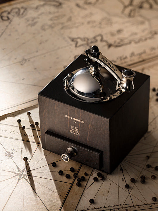 Peugeot | Roellinger Pepper Mill, Chocolate, showcased on a nautical map, featuring a dark wood body with a polished chrome crank and lever mechanism.