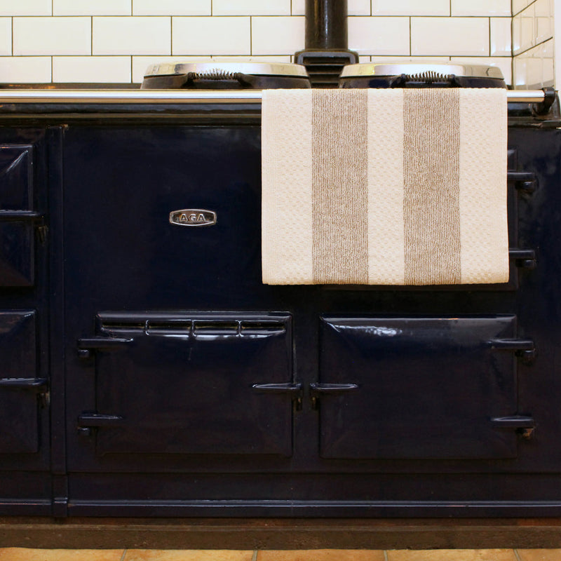 Earth & Nest | White Range Towel on a stove rail, showcasing its popper fastening for secure placement. Ideal for maintaining a clean, dry kitchen environment.