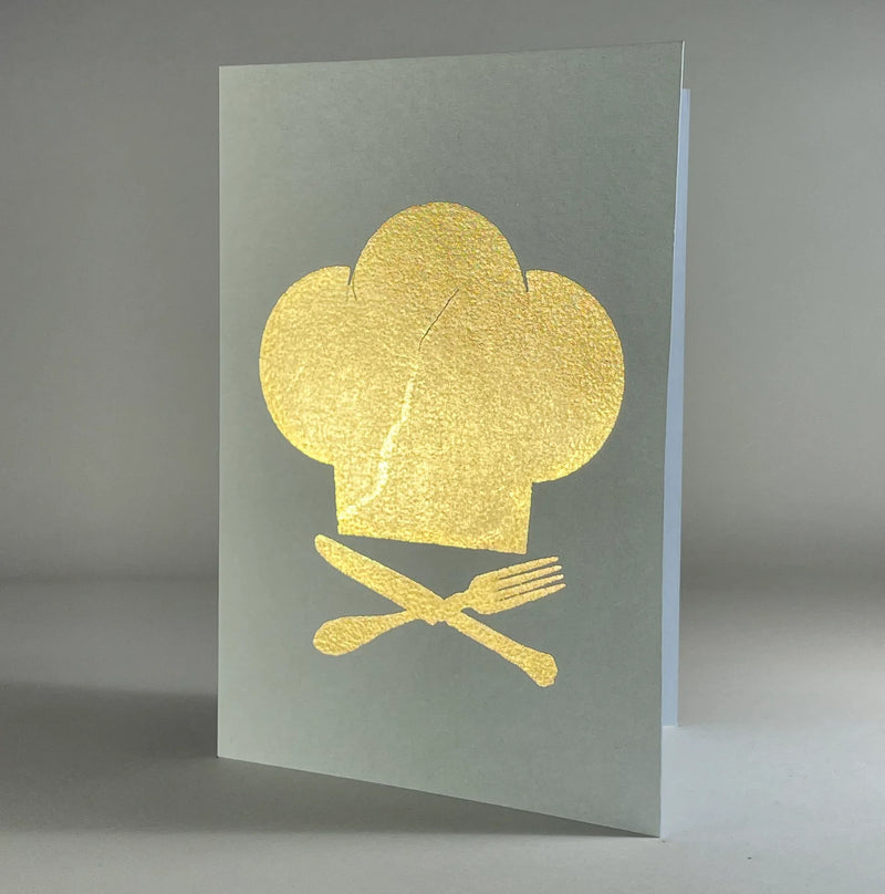 Catherine Greenup Cards | Chef Hat on Moss: A greeting card featuring a gold-foil chef's toque with crossed utensils, perfect for culinary-themed gifting from Athens Cooks.