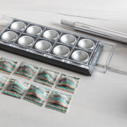 Marcato Ravioli Tablet Pasta Makers (Black) with a tray of neatly arranged square ravioli, accompanied by a pasta rolling pin for easy cutting and sealing.