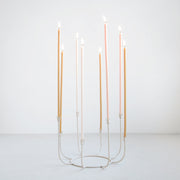 The Floral Society | Beacon Long-Stem Candelabra, Dune, showcasing nine lit taper candles in a handmade, wire-frame design with curved stems and tulip candle cups.