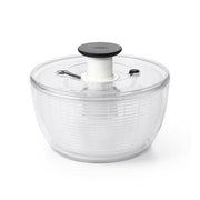 OXO Good Grips Salad and Herb Spinner with soft non-slip knob and built-in brake, ideal for drying and serving greens effortlessly in a kitchen setting.