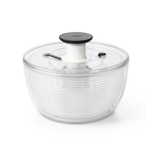 OXO Good Grips Salad and Herb Spinner with soft non-slip knob and built-in brake, ideal for drying and serving greens effortlessly in a kitchen setting.