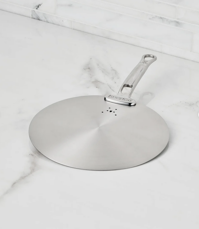 Hestan | Provisions Stainless Steel Universal Lids, Medium, on marble countertop, features steam vents and handle, ideal for skillets, enhancing kitchen organization and efficiency.