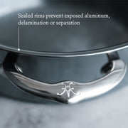 Hestan | Cookware, 12.5 Titanium Skillet close-up, showcasing sealed rims preventing aluminum exposure, with a polished handle featuring an embossed decorative logo.