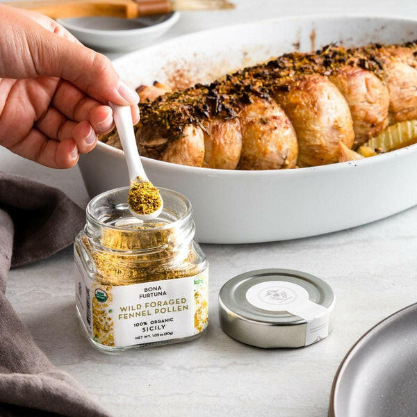 Close-up of a hand holding a white spoon with Bona Furtuna's Mama Rose's Herb Blend, emphasizing Sicilian flavors for versatile seasoning in cooking.