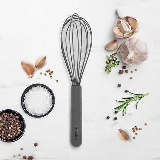GreenPan | Premium Silicone Whisk, gray-handled, surrounded by cooking ingredients including garlic, salt, peppercorns, coriander, rosemary, and thyme on a white surface.