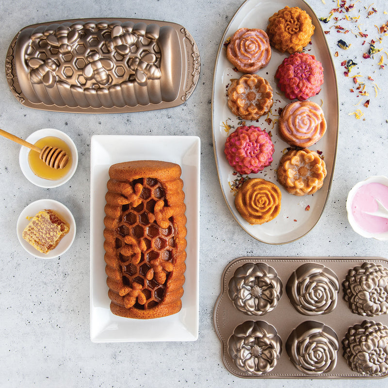 Nordic Ware | Floral Cakelet Pan with various pastries, showcasing detailed flower-shaped molds perfect for baking mini Bundt cakes.