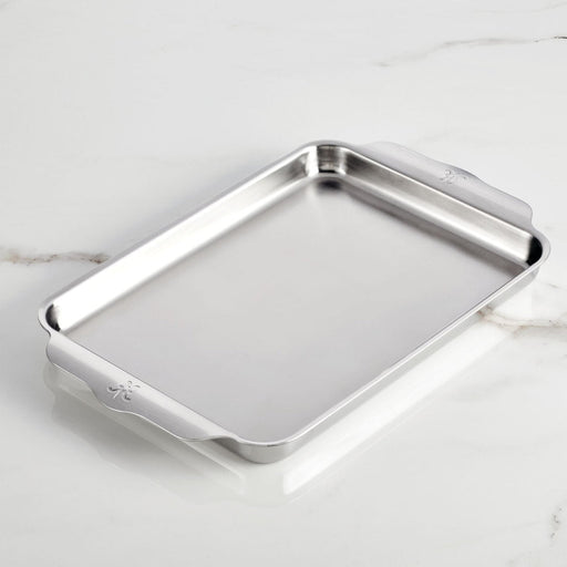 Hestan | Oven Bond Tri-Ply Bakeware, Quarter Sheet Pan with curved handles, sits empty on a countertop, showcasing its stainless steel craftsmanship and durable design.
