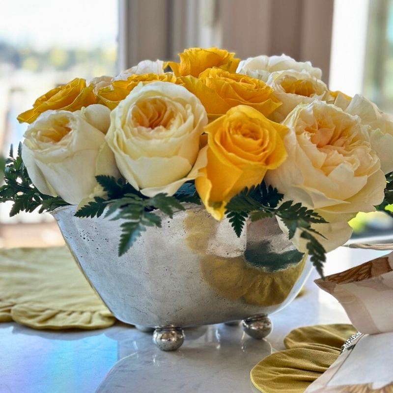 Vintage Scalloped Bowl by Arte Italica & Crown Linen Designs, showcasing cream-white and golden-yellow roses, set on a polished stone tabletop with nearby mustard-yellow fabric accents.