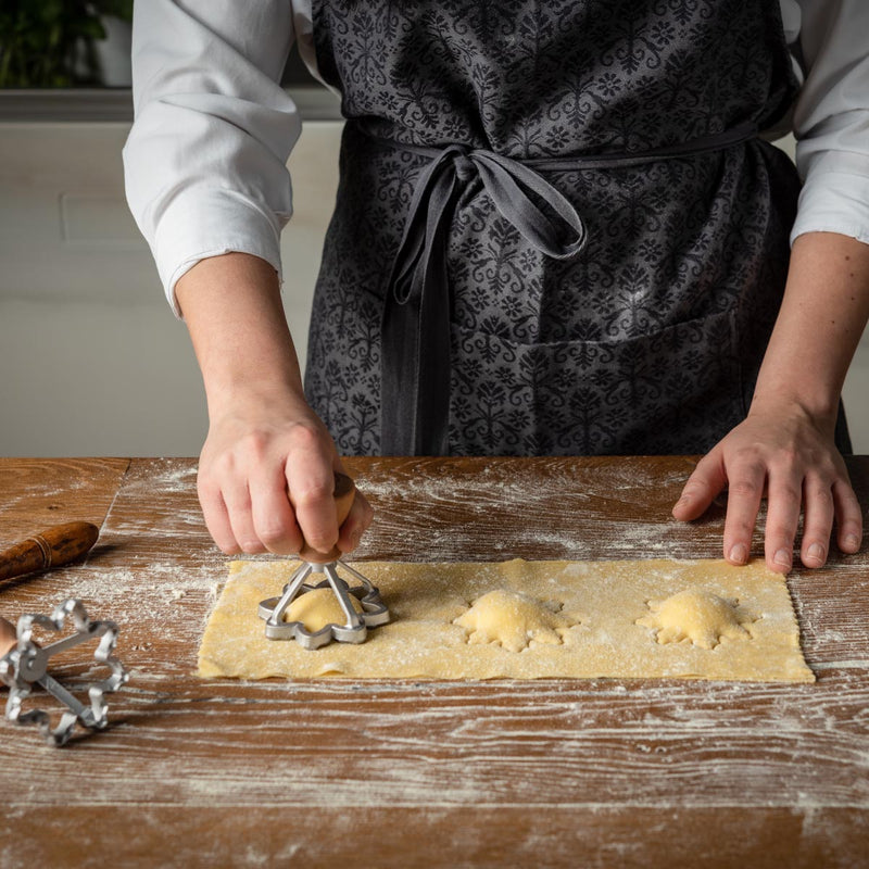 Person using Marcato 3 Flower Ravioli Stamp on dough, crafting homemade ravioli with precise cut and seal, ideal for fresh pasta making.