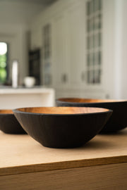 Creating Comfort Lab | Handmade Ukrainian Charred Wooden Salad Bowls, Set of 3: Small, Medium, Large, shown with a dark exterior and natural interior on a kitchen countertop.
