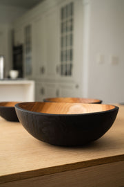 Creating Comfort Lab | Handmade Ukrainian Charred Wooden Salad Bowls, Set of 3, displayed on a light wood countertop, showcasing their distinct charred exterior and natural interior.