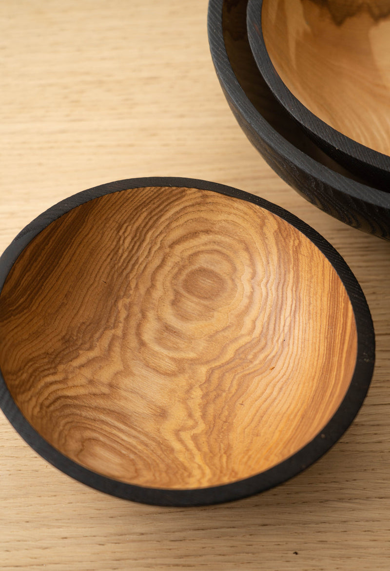 Creating Comfort Lab | Handmade Ukrainian Charred Wooden Salad Bowls, Medium, showcasing a nested set with warm wood interiors and dark charred exteriors on a light wood surface.
