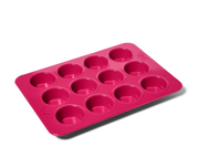 Great Jones | Stud Muffin - Raspberry: Close-up of a pink nonstick, nontoxic muffin pan fitting 12 muffins, ensuring even heat distribution and easy cleanup.