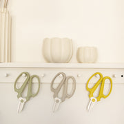 The Floral Society | Japanese Floral Clippers, Citrine, hang below a neutral-tone wall shelf with ceramic vessels, ideal for precise garden and flower tasks.