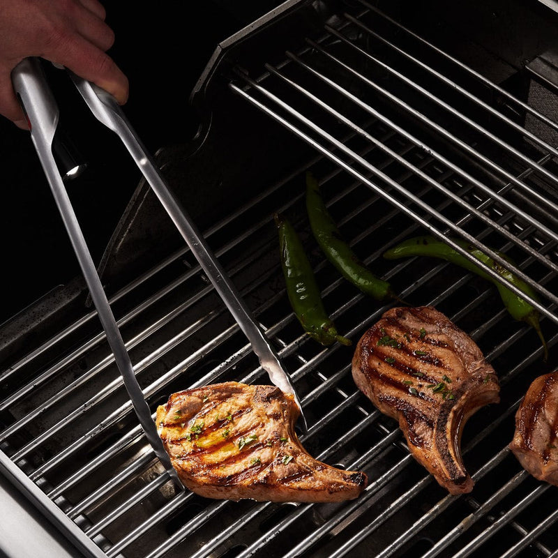 GrilLight | Gift Set - 2 Piece Spatula + Tongs in use, grilling meat with LED illumination on a barbecue grill.