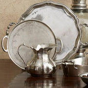 Vintage Small Scalloped Pitcher by Arte Italica & Crown Linen Designs, handcrafted Italian pewter, displayed with antique silver serving pieces, emphasizing timeless elegance and artisan craftsmanship.