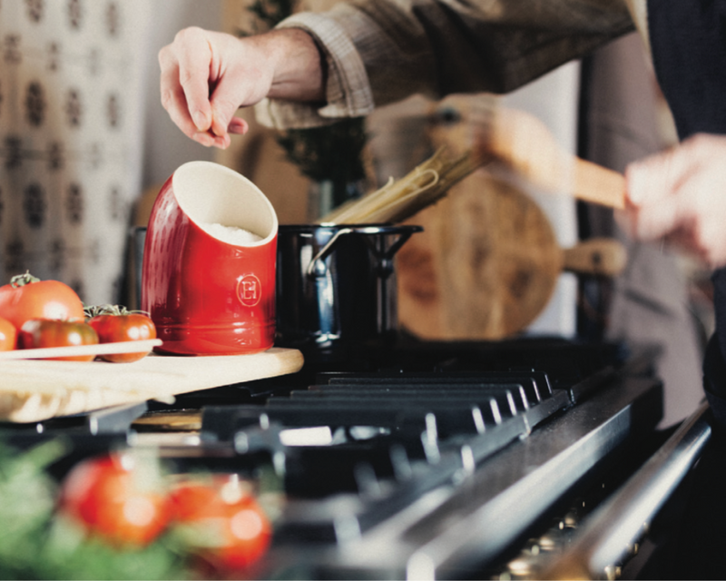 Emile Henry Modern Classics Loaf Pan, Rouge, 9 x 5, featured in a home kitchen setting with cooking and meal prep on a gas stove.